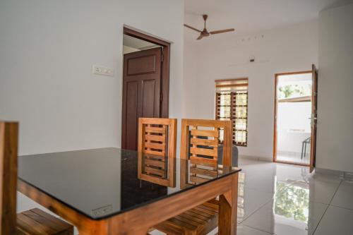 a dining room with a glass table and two chairs at Shimano Square in Varkala