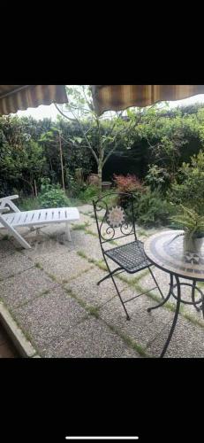 um pátio com uma mesa, uma cadeira e um banco em Grazioso monolocale con giardino em Pregnana Milanese