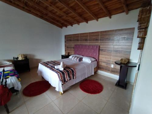 1 dormitorio con 1 cama grande con alfombras rojas en Alojamiento en Jardin Cabaña las Aguilas en Jardin