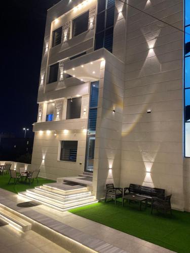 un edificio con panchine di fronte ad esso di notte di رويال جروب اربد Royal Group Hotel a Irbid
