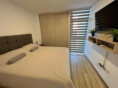 a bedroom with a bed and a flat screen tv at Departamento moderno en equipetrol in Santa Cruz de la Sierra