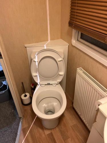 a bathroom with a toilet with the seat up at CW27 St Osyth Holiday Park with disability Ramp in Saint Osyth