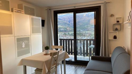 a room with a table and a balcony with a view at La Méa in Barcelonnette