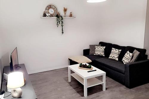 un soggiorno con divano nero e tavolo bianco di Le Cocon de L'Horme 30 min LYON Parking privé a LʼHorme