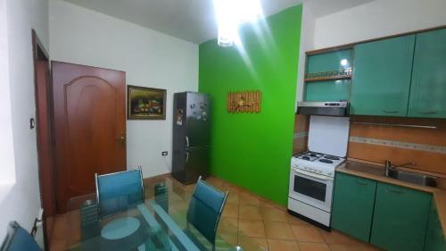 uma cozinha verde com uma mesa e um frigorífico em Beautiful flat in the center of Shkodra, Albania em Shkodër