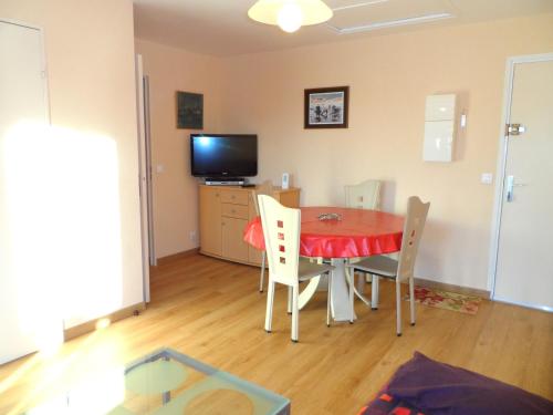 une salle à manger avec une table, des chaises et une télévision dans l'établissement Appartement 2P à Cabourg, 4 personnes, proche Thalasso, balcon ouest, animaux acceptés - FR-1-487-284, à Cabourg