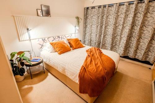 a bedroom with a bed with orange pillows and a window at Exquisite Living with BicoccaStays in Aberdeen