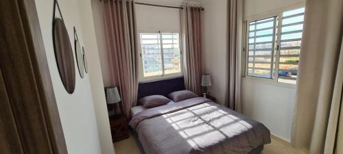 um pequeno quarto com uma cama e 2 janelas em Les portes de Gueliz - apartment 6 people em Marrakech