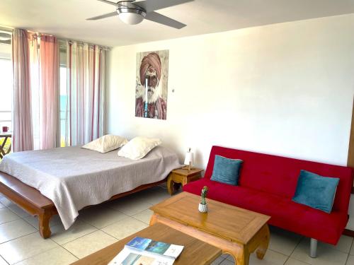 ein Schlafzimmer mit einem Bett und einem roten Sofa in der Unterkunft Studio Marigot, Vue Panoramique in Saint Martin