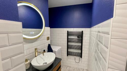 baño con paredes azules, lavabo y espejo en Le Perchoir - WIFI - Gare - Proche tous commerces, en Sarrebourg