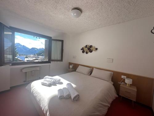 um quarto com uma cama grande e toalhas em Delizioso appartamento nelle Dolomiti em Madonna di Campiglio