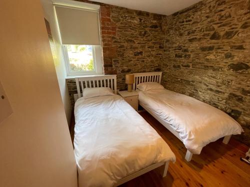 two beds in a room with a brick wall at Lovely apartment overlooking the harbour and bay in Ardglass