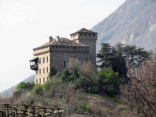 een groot kasteel op een heuvel met een berg bij La maison de Daniela in Settimo Vittone
