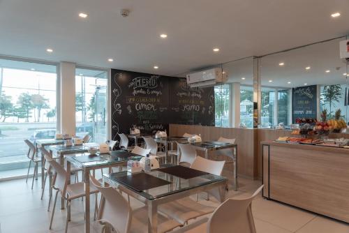 a restaurant with tables and chairs and a chalkboard wall at Hotel Praia Bonita Jangadeiros Pajuçara in Maceió