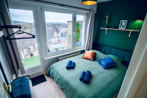 Un dormitorio con una cama con almohadas azules y una ventana en Le Perchoir - WIFI - Gare - Proche tous commerces, en Sarrebourg
