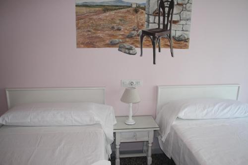 Habitación con 2 camas y una silla en la pared. en Hostal Isabel II, en Figueres