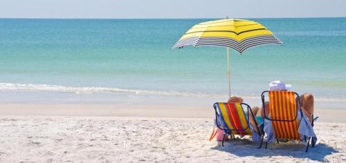 two people sitting in chairs under an umbrella on the beach at B&B Tio Pepe in Roseto degli Abruzzi