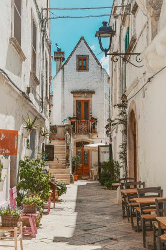 une allée avec des tables et des chaises et un bâtiment dans l'établissement Via Dura - Apulian Cozy House, à Locorotondo