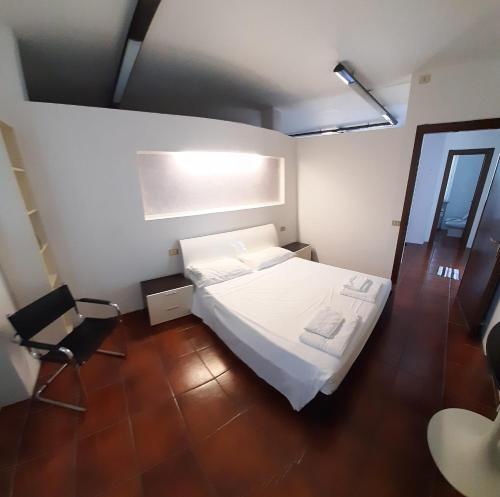 1 dormitorio con 1 cama blanca y 1 silla en Volta 8, en Cassano Magnago