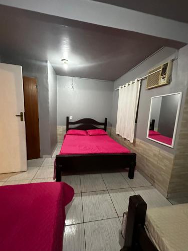 um quarto com 2 camas com lençóis cor-de-rosa e um espelho em Casinha Vilarejo em Cabo Frio