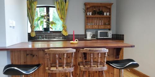 a kitchen with a wooden counter with stools at Cosy two bedroom lodge on the edge of Raheen Woods in Tuamgraney