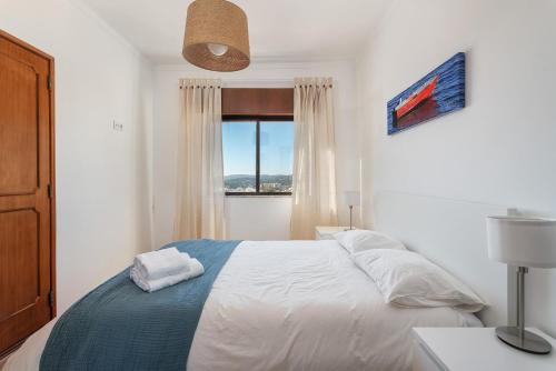 ein weißes Schlafzimmer mit einem Bett und einem Fenster in der Unterkunft Spacious & Sunny Flat - Loulé in Loulé