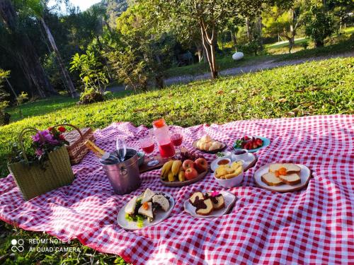 イビウーナにあるHotel Fazenda Morros Verdes Ecolodgeのピクニックテーブル(赤白の毛布の上に盛り付けられた皿)