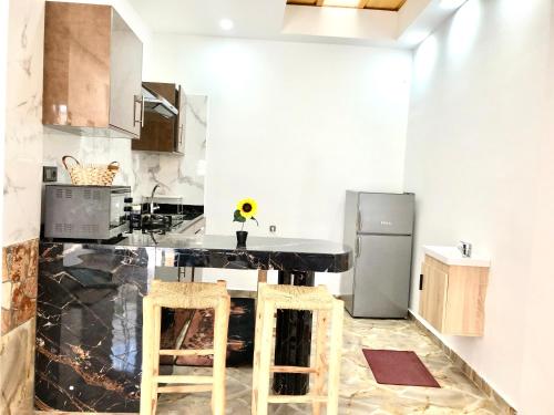 a kitchen with a black counter and a refrigerator at Padova Surf House in Imsouane