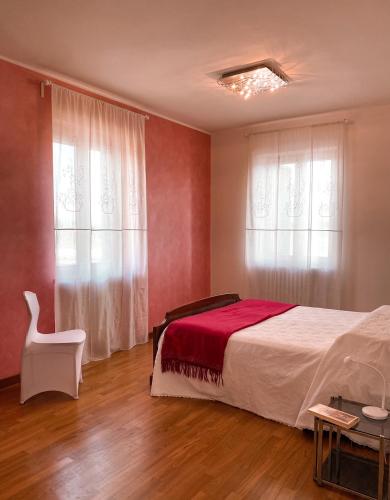 a bedroom with a bed and a chair and a window at Casa Gallinotto in Alba