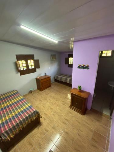 um quarto com paredes roxas, uma cama e uma mesa em Sítio Caminho das Acácias em São Lourenço da Mata