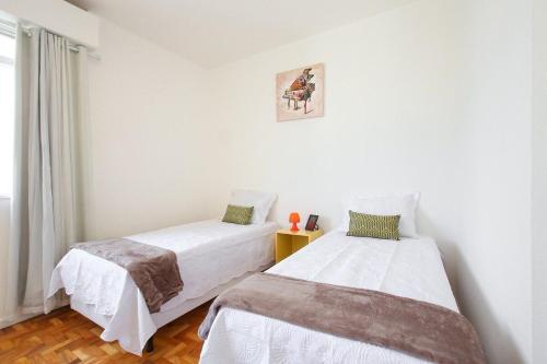 2 camas en una habitación con paredes blancas en Dona Acibe Apartments by BnbHost, en São Paulo