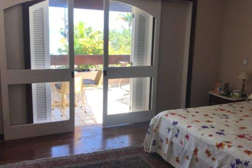 Schlafzimmer mit einer Tür, die auf eine Terrasse mit einem Bett führt in der Unterkunft Um sonho de casa frente à laguna in São Pedro da Aldeia