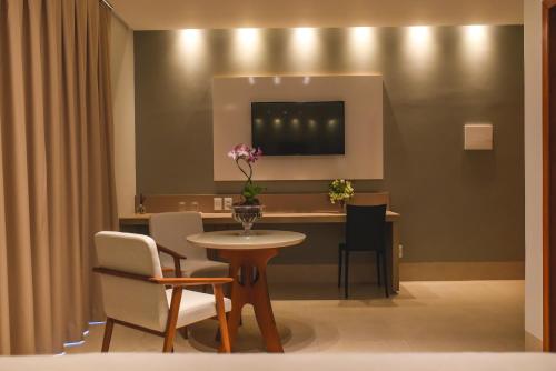 une salle à manger avec une table, des chaises et une télévision dans l'établissement Hotel D'Leon, à Gurupi