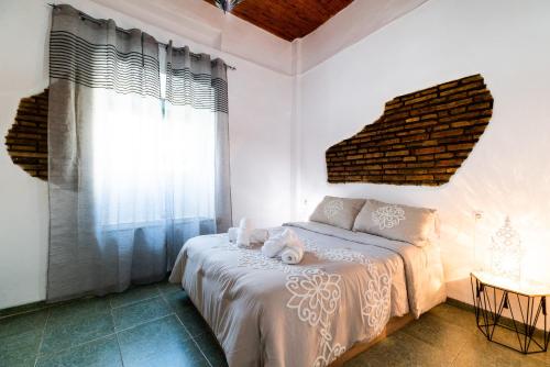 a bedroom with a bed with white sheets and a window at La casa del Sacristán. in Granada
