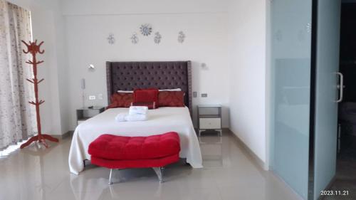 a bedroom with a large bed with a red chair at HOTEL TERRAZAS DE VILLA in Moquegua