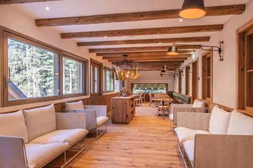 a room with white chairs and a table and windows at Berghaus Schröcken - Hotel Apartments Spa in Schröcken