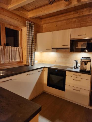 a kitchen with white cabinets and a black appliance at Lipphütte Top Lage mit traumhafter Aussicht in Rauris