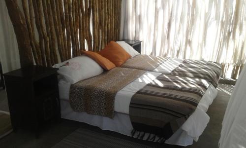 a bedroom with a bed with pillows and a window at Paradise Camp delux Rooms in Groutfontein