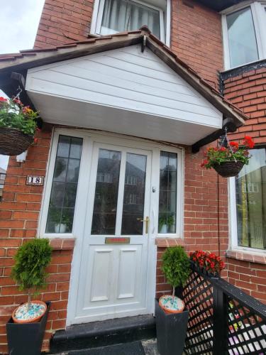 a white door on a brick house with two potted plants at Petals Rm1 in Belle Isle