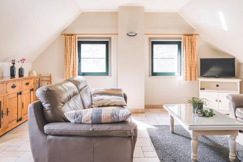 a living room with a chair and a table at De Burkelhoeve appC in Maldegem