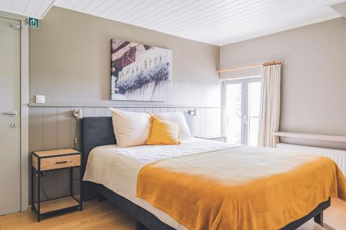 ein Schlafzimmer mit einem Bett mit einer gelben Decke in der Unterkunft De Burkelhoeve appC in Maldegem