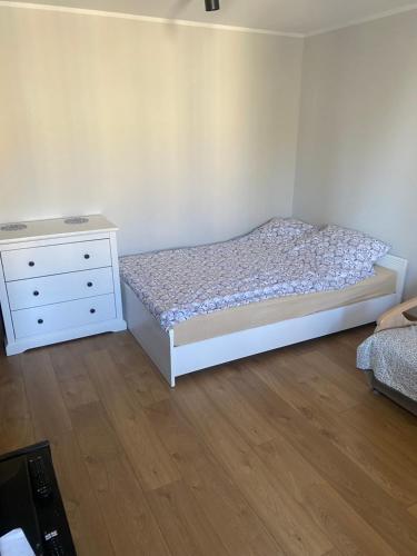 a bedroom with a white bed and a dresser at Apartament Centrum Malbork in Malbork