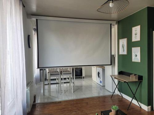 - un grand écran dans une chambre avec une table et des chaises dans l'établissement La rétro- séance, à Soissons