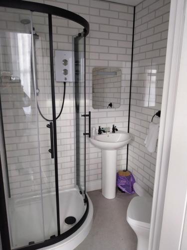 a bathroom with a shower and a sink and a toilet at Delamere Hotel in Blackpool