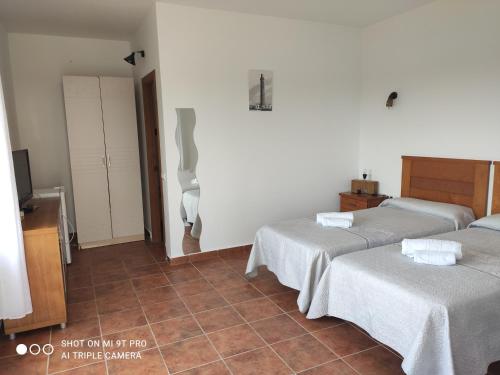 a bedroom with two beds and a tiled floor at Vistas al faro in Cádiz