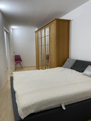 a bedroom with a large bed and a wooden cabinet at Helle Zwei-Zimmer-Stadt-Wohnung am Bismarkplatz mit Tiefgarage in Landshut