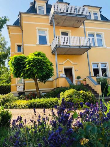 a yellow house with a garden in front of it at Pension&Wellness-Oase-Nossen in Nossen
