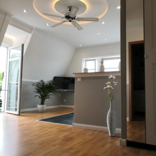 a living room with a ceiling fan and a vase with flowers at Pension&Wellness-Oase-Nossen in Nossen