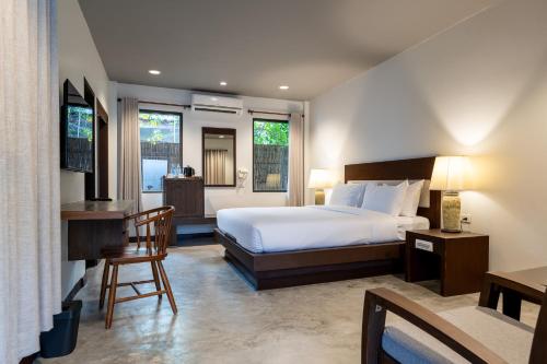 a bedroom with a bed and a desk and two windows at RB Resort in Pattaya Central