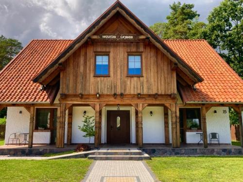 a large wooden house with an orange roof at Mazurska Gajówka in Ruciane-Nida